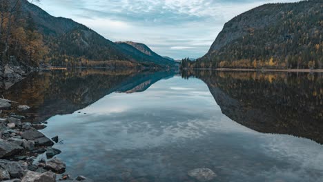 Vorbeiziehende-Wolken-Spiegeln-Sich-Im-Ruhigen-See,-Umgeben-Von-Bewaldeten-Bergen