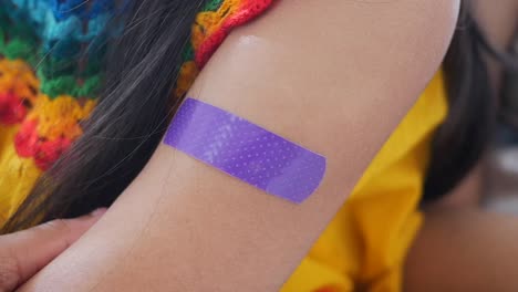 close-up of a person's arm with a purple bandage after an injection or vaccination