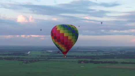 Vista-Aérea-Del-Colorido-Globo-Aerostático-Volando-Sobre-La-Pradera,-Países-Bajos