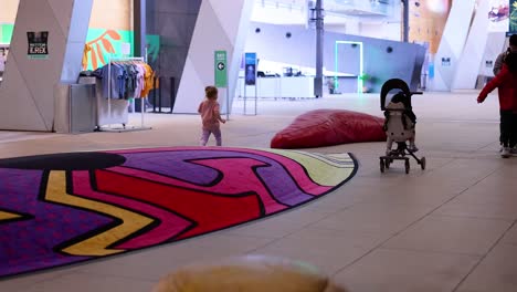 niño explora el colorido espacio del museo con un cochecito