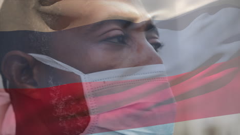 animation of flag of russia waving over man wearing face mask during covid 19 pandemic