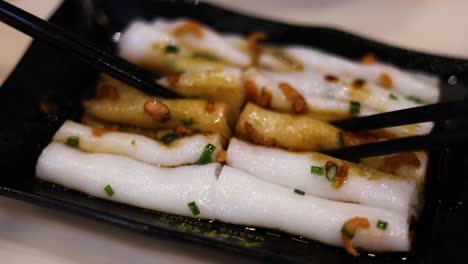 chopsticks picking up rice noodle rolls