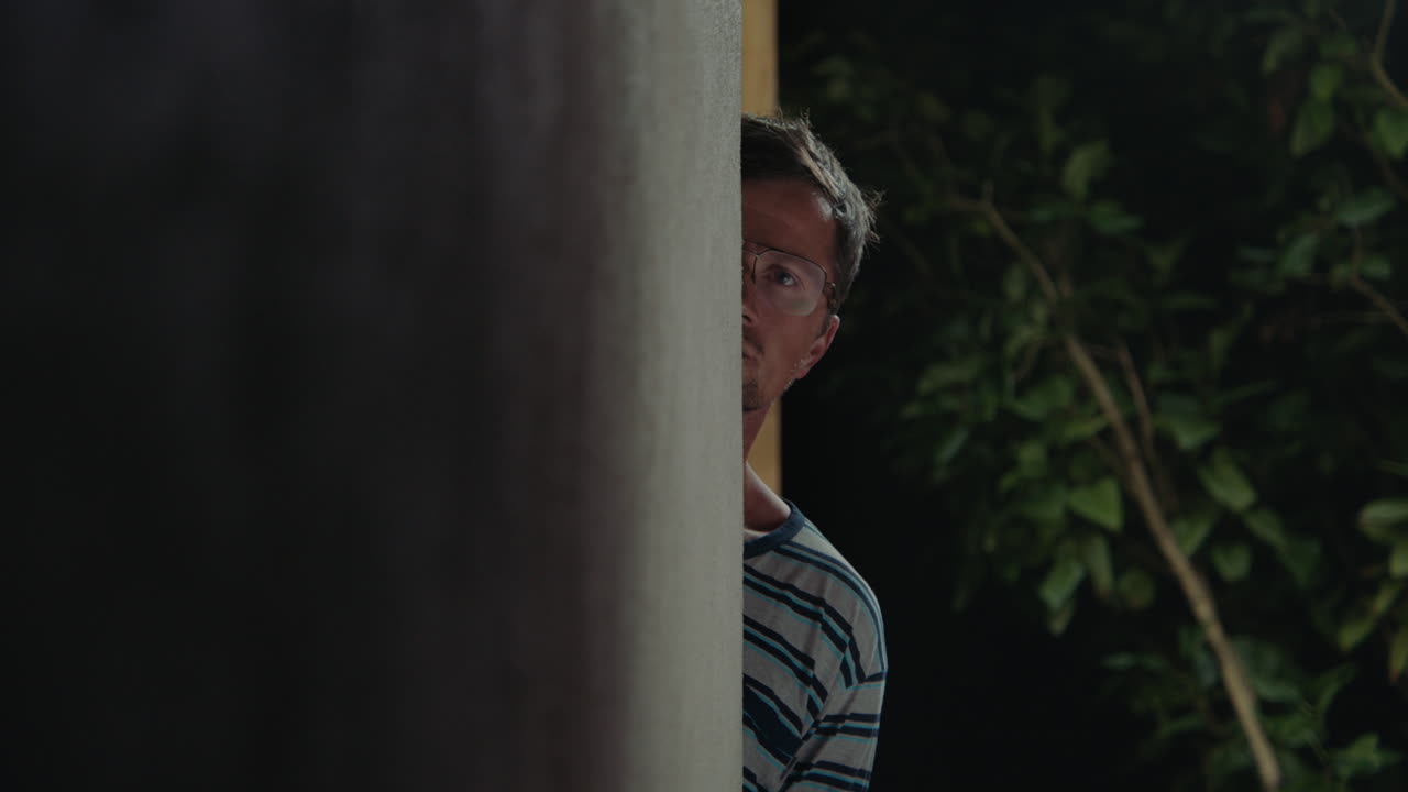 Man Hiding Behind Wall at Night