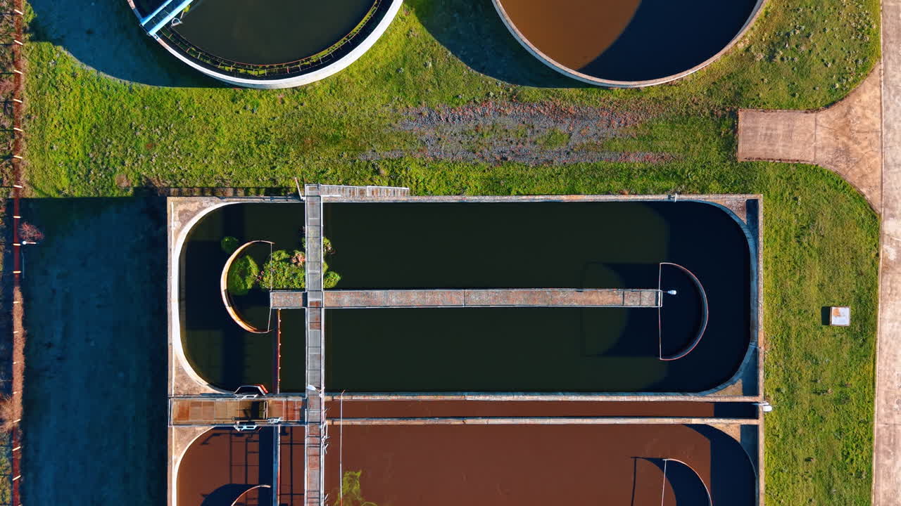 Aerial view of sewage treatment plant infrastructure and tanks. Top down shot of large industrial facility for water filtration and sanitation in rural landscape