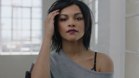 portrait-of-independent-young-mixed-race-woman-looking-serious-pensive-at-camera-running-hand-through-hair-strong-focused-intense-female