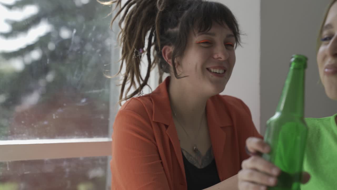 mujer joven con piercings hablando mientras su amiga come pizza y bebe cerveza