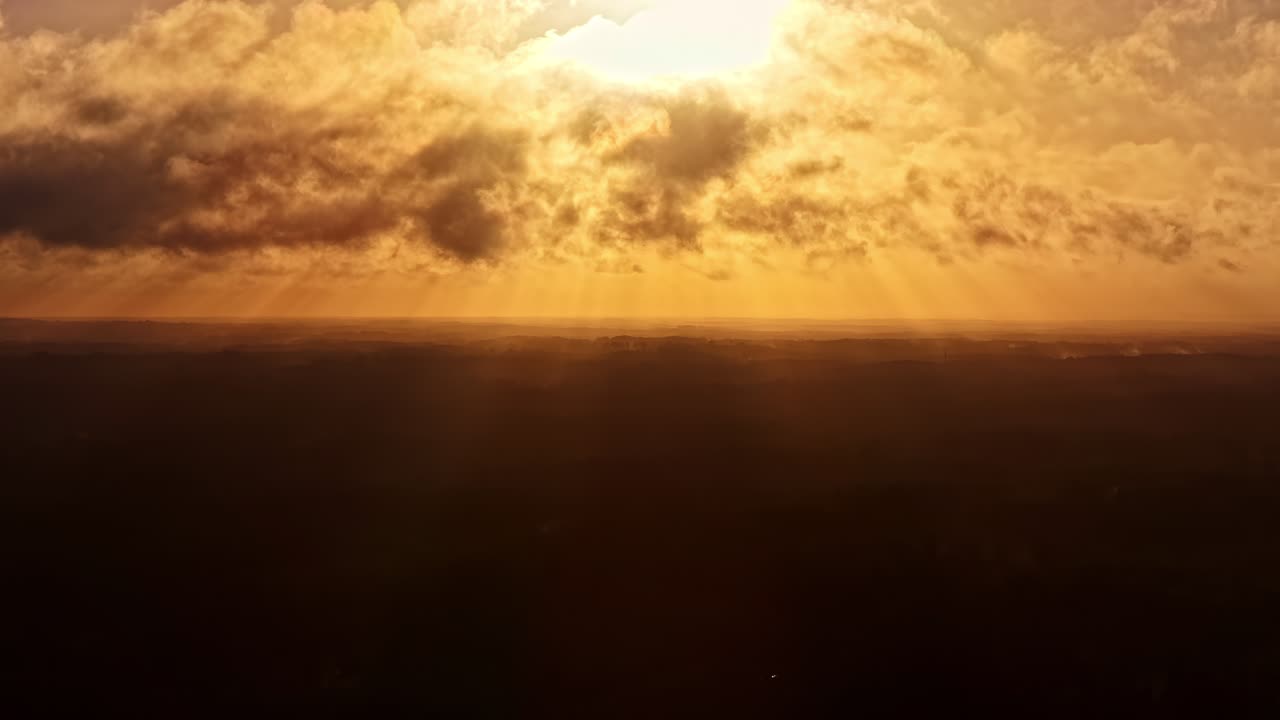 Majestic sunbeams breaking through clouds in dramatic golden hour sky