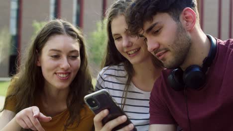 Group-of-students-browsing-phone-next-to-to-university-campus