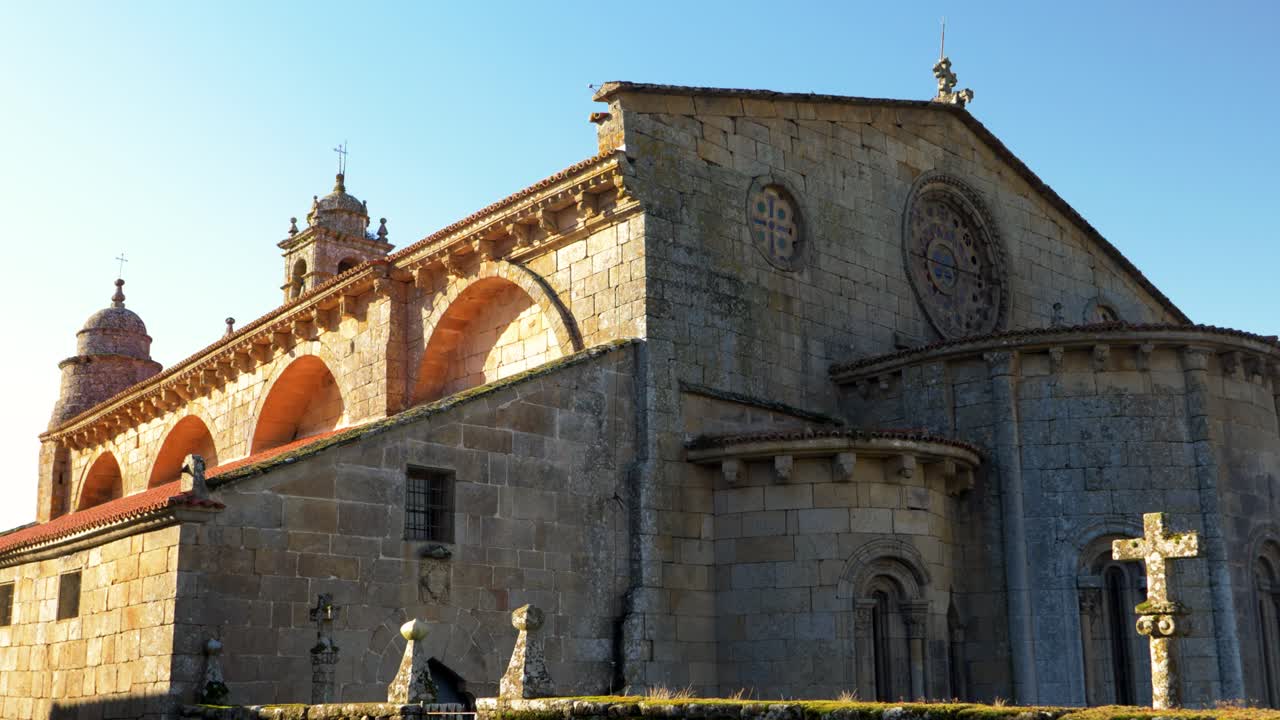 Stone facade and bell tower of the Church of Santa Mariña in Allariz, focusing on the intricate architectural details.