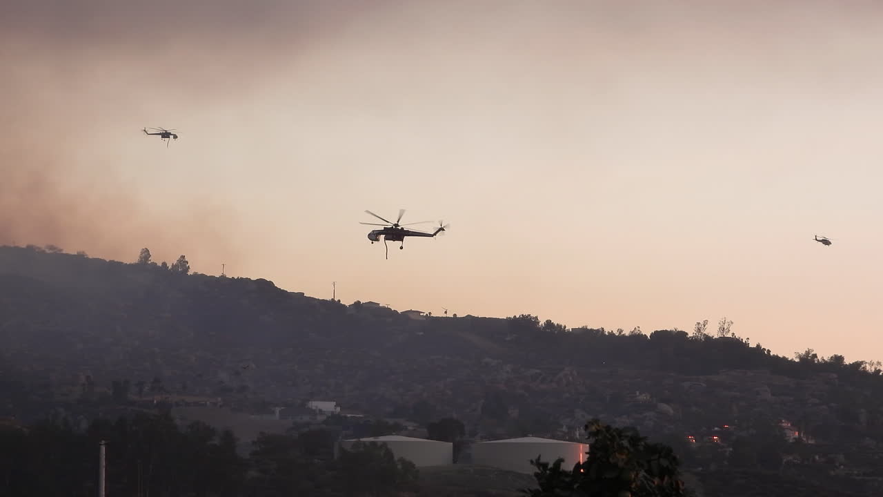 helicópteros vuelan a través del humo por incendios forestales en las colinas de california, ee.uu.