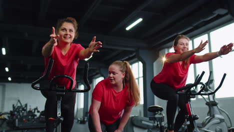 Gesunde-Kaukasische-Gruppe-Von-Frauen-Trainieren-Auf-Einem-Stationären-Fahrrad-Im-Fitnessstudio