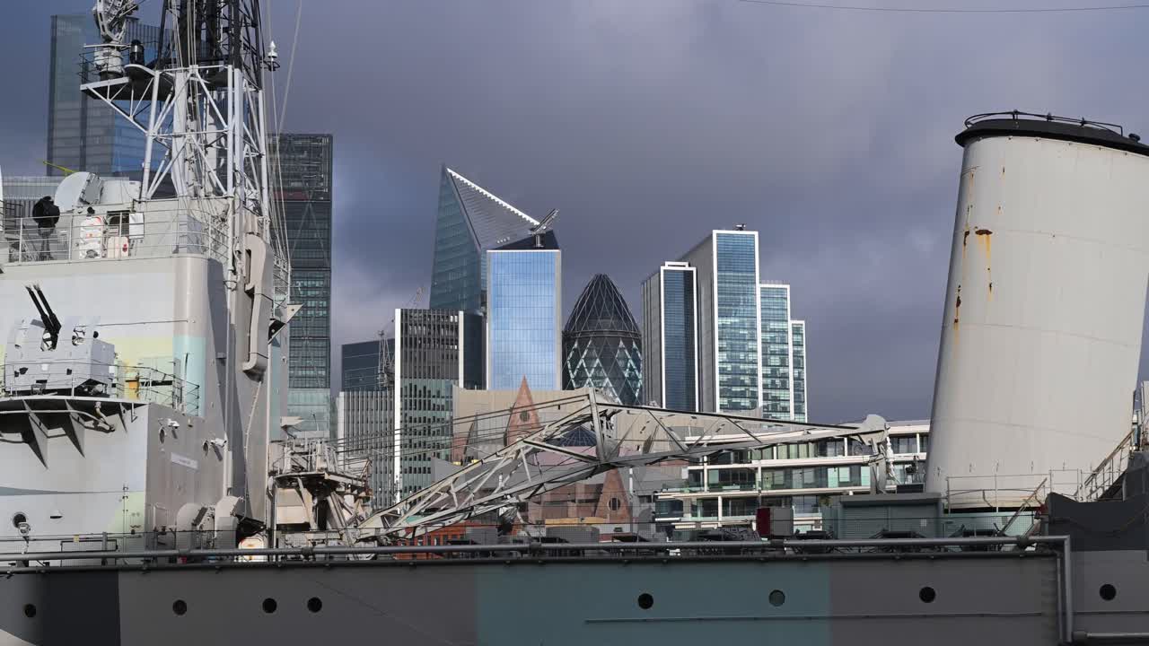 De historische grijze romp van de HMS Belfast in contrast met het moderne geometrische glas van The Scalpel