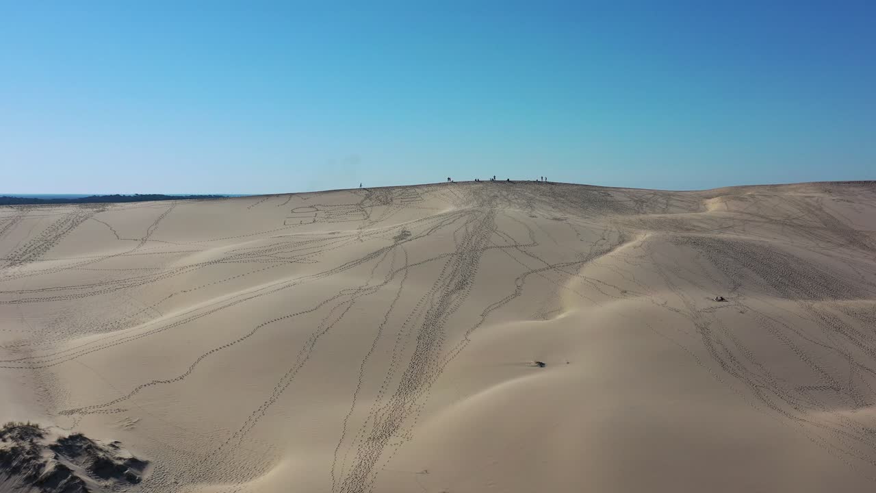 песчаный холм дюне-ду-пилат во франции с людьми, идущими вдоль вершины с отпечатками ног, отмеченными в песке, воздушный перелет.