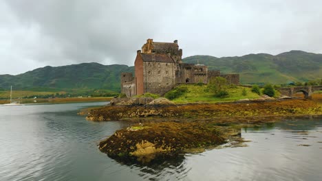 Barrido-Aéreo-Bajo-Del-Castillo-Escocés,-Eilean-Donan,-En-Loch-Duich-En-Las-Tierras-Altas-De-Escocia,-Escocia,-Reino-Unido