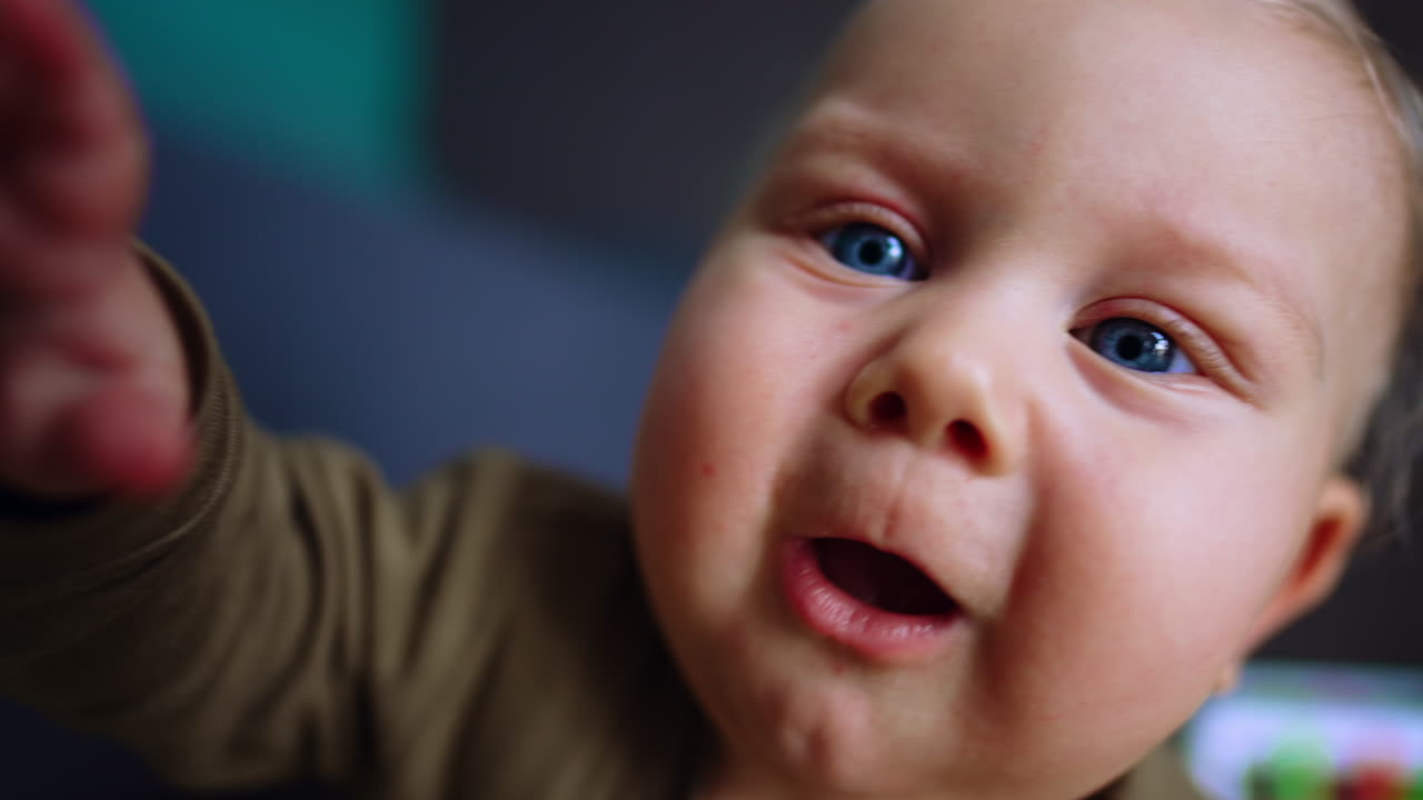 Chubby face of a cute Caucasian blue-eyed baby. Close up. Curious infant trying to get a camera.