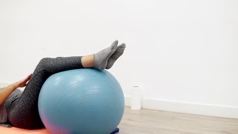 Eine-Junge-Kaukasische-Frau,-Die-Eine-Korrekturübung-Mit-Einem-Physio-Übungsball-In-Einer-Sportphysiotherapie-Klinik-Durchführt