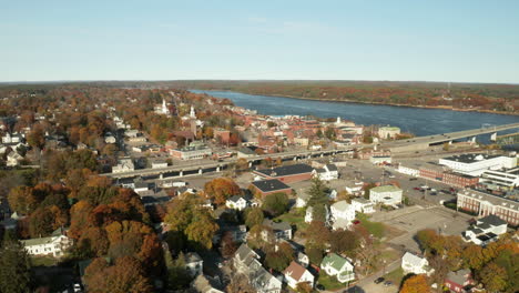 drone shot of city on river banks in autumn, bath, maine