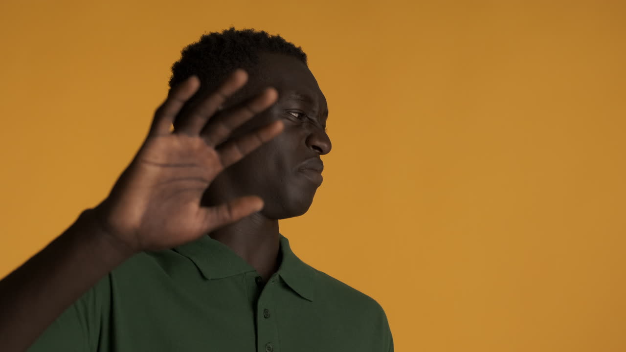 Disgusted African american man on yellow background.