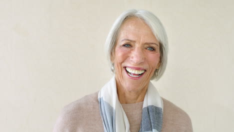 Portrait-of-smiling-senior-woman-against-a-studio