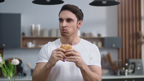 hombre hambriento comiendo hamburguesa en la cocina