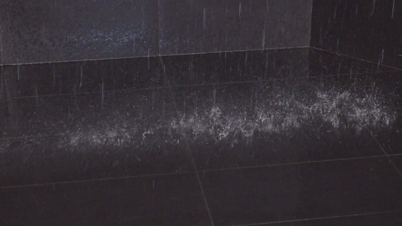Water drops fall at the black tiled floor