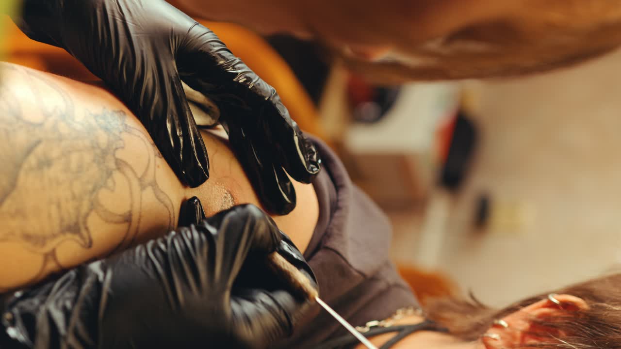 Hands of Tattooist in Gloves Injecting Ink into Skin with Needle