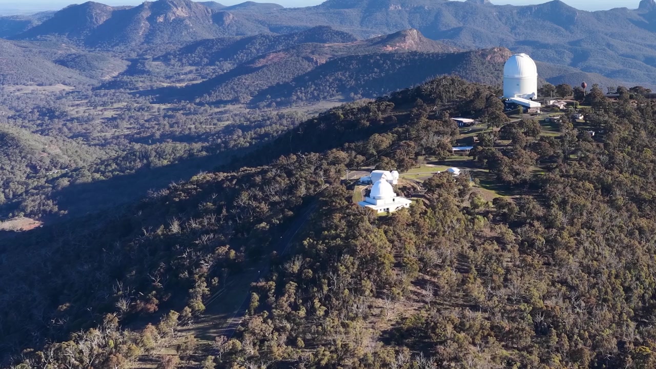Ampia ripresa aerea di cupole di telescopi in cima a una cresta montuosa nel Parco Nazionale di Warrumbungle.