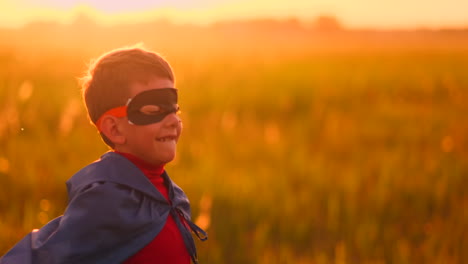 The-boy-in-the-mask-and-Cape-of-a-super-hero-at-sunset-in-a-field.