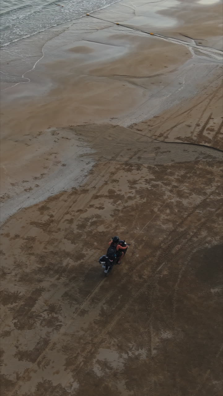 Motociclista che guida una moto su una spiaggia da una vista aerea