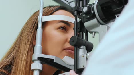 ojos medidos con refractómetro en un óptico u oftalmólogo. oftalmólogo midiendo la presión intraocular de una mujer joven en una clínica