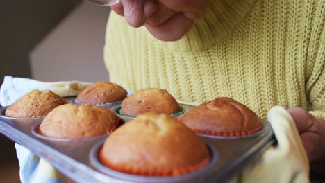 mujer mayor oliendo muffins recién horneados en la bandeja 4k 4k