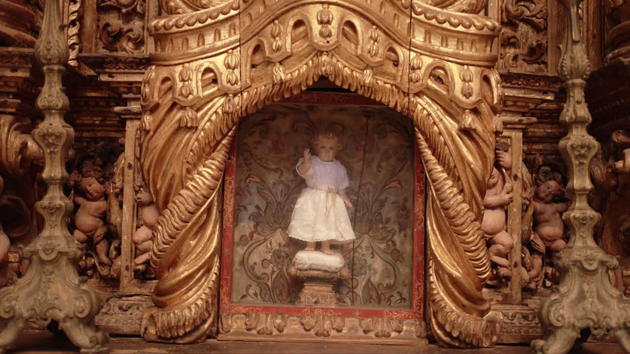 Baroque style shrine with a sacred infant statue in an elaborate golden altar