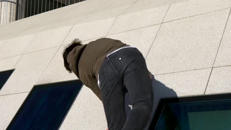 primer plano de un joven atleta de parkour haciendo un wallspin en un edificio urbano en cámara lenta