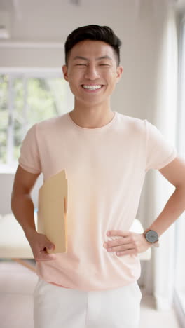 vertical video of portrait of happy asian male physiotherapist in studio, slow motion