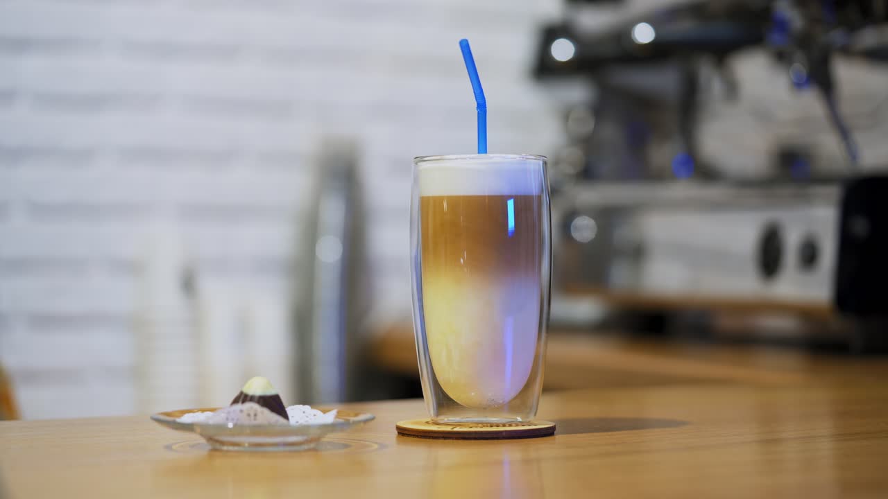 Serving beverage. Tasty dessert on the table. Woman puts straw into a glass of fresh drink and some sweet on a plate. Close-up.