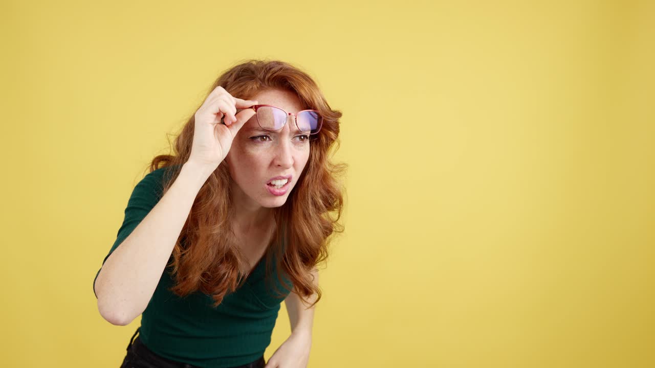 Woman with red hair and glasses squinting and looking intently