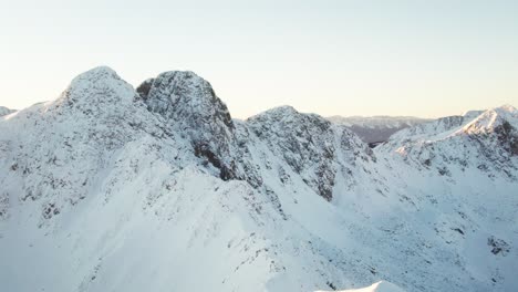 drone moves along snowy mountain summits in andorra, revealing a vast white alpine landscape.