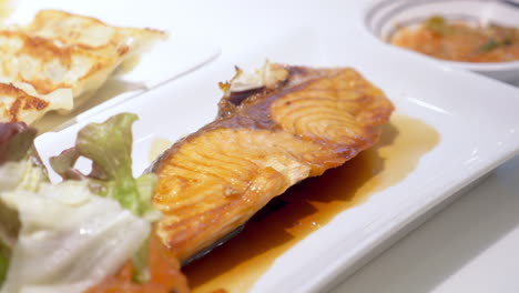 picking pieces of salmon steak served in a platter in a restaurant in bangkok, thailand