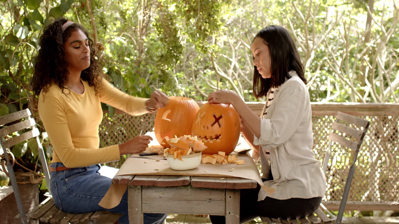 Halloween time, carving pumpkins, multiracial female friends on a porch together