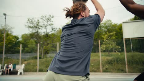 Close-up-shot-of-a-man-in-a-gray-T-shirt-passing-his-friend-in-a-white-T-shirt-in-basketball,-scoring-a-brilliant-goal-and-very-happy-about-his-success