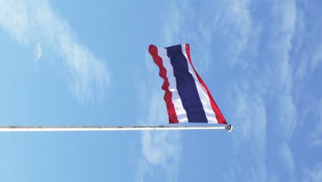 Vertical-of-Waving-the-Kingdom-of-Thailand-flag-on-a-pole-with-blue-sky-and-white-clouds-in-the-background