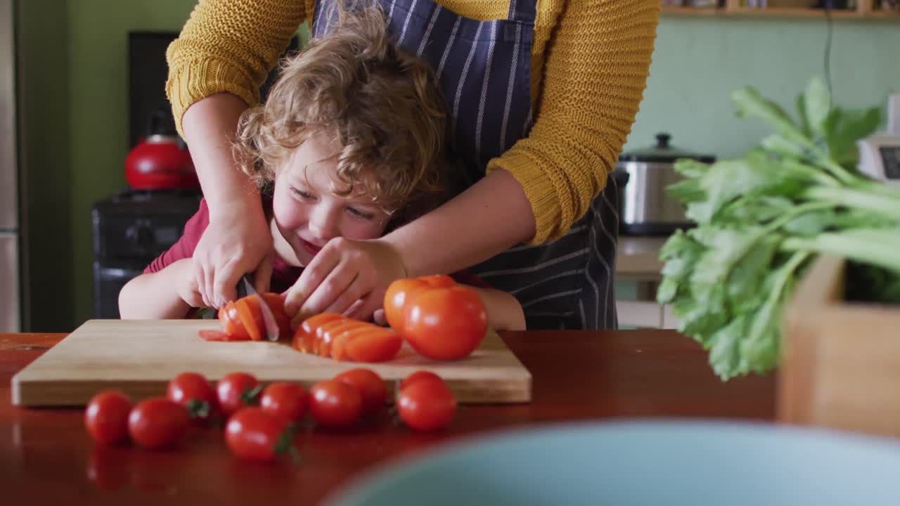 행복한 백인 어머니와 아들이 부 ⁇ 에서 채소를 자르고 있습니다.