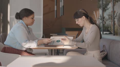 two businesswomen shaking hands after making agreement at meeting