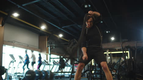 Energetic-athlete-using-battle-ropes-at-gym.-Sport-man-doing-repetitions-in-club