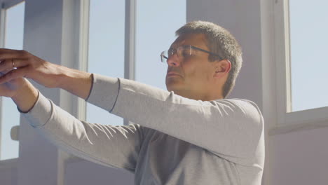 man performing slow tai chi movements while sitting on floor