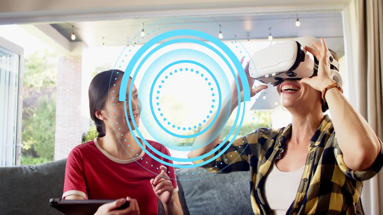 Two women on couch, left tapping tablet launching VR, right donning headset gesturing at AI overlay