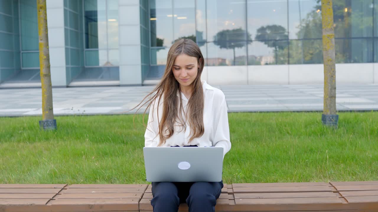 mujer joven sentada afuera y trabajando en una computadora portátil, en cámara lenta