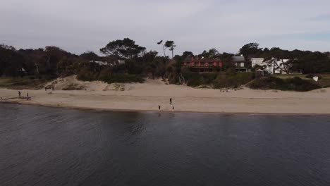 Kamerafahrt-Aus-Der-Luft-Von-Zwei-Kindern,-Die-Am-Sandstrand-Des-Flusses-Maldonado-In-Uruguay-Spielen