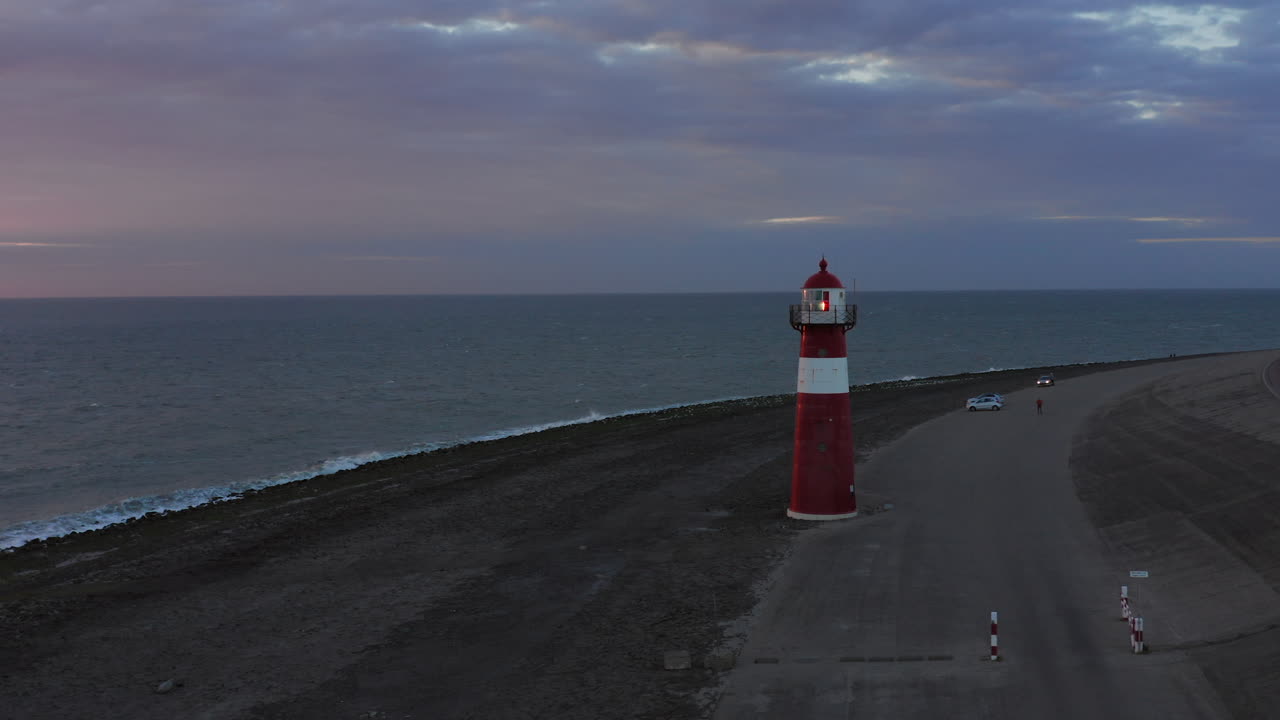바람이 많이 부는 밝은 오렌지색 일몰 동안 웨스트카펠의 등대