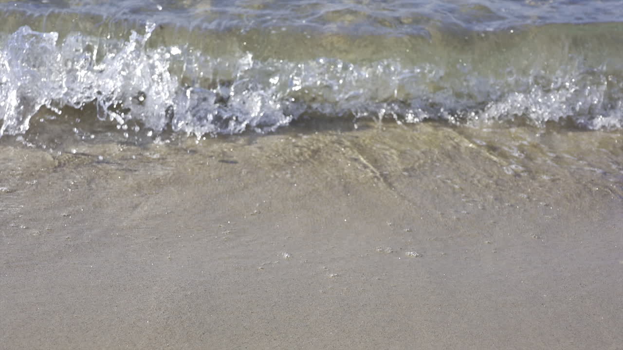 Close up of waves crashing on the beach in daylight